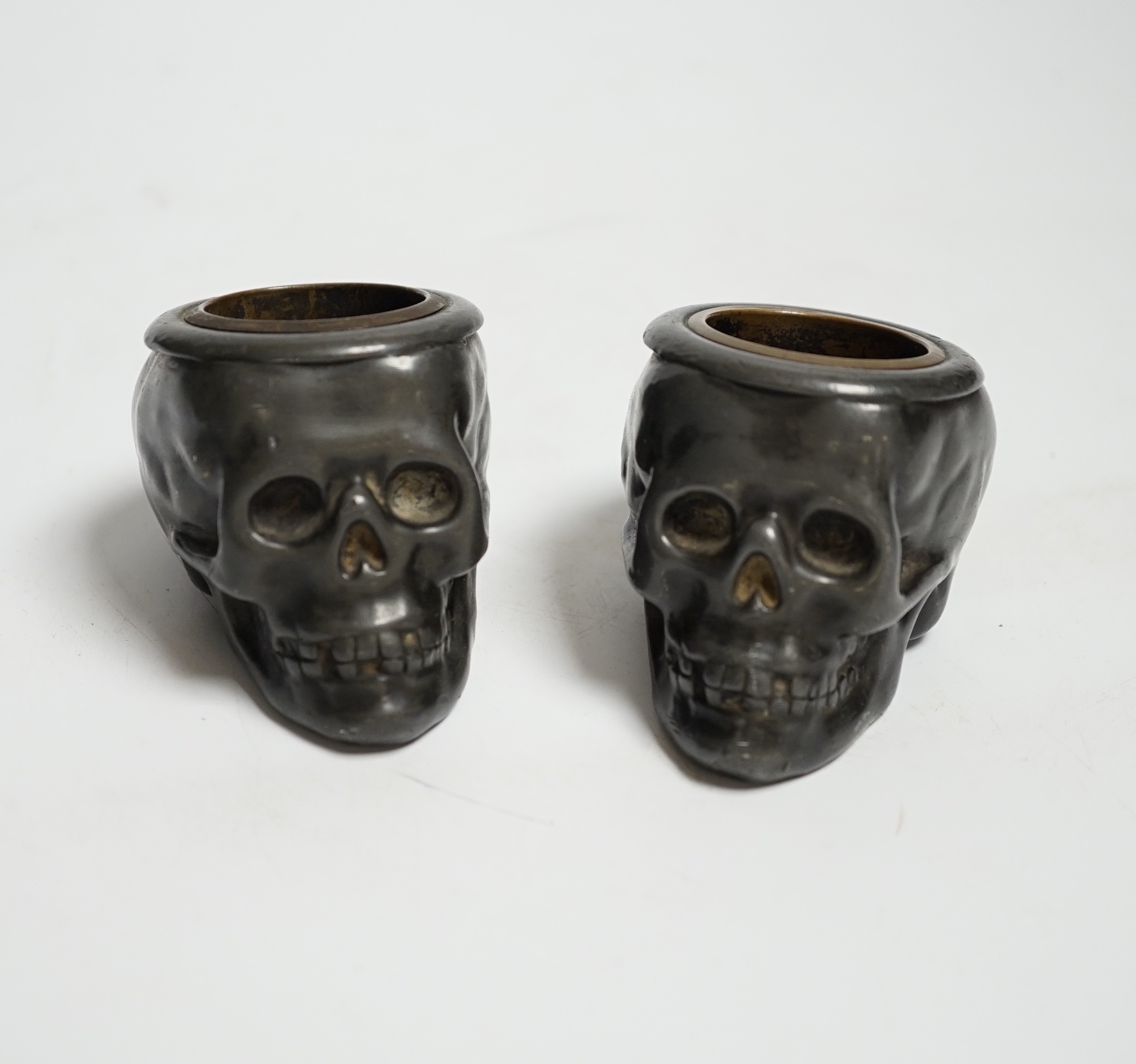 A pair of late 19th century skull shaped pewter match holders, 5cm tall